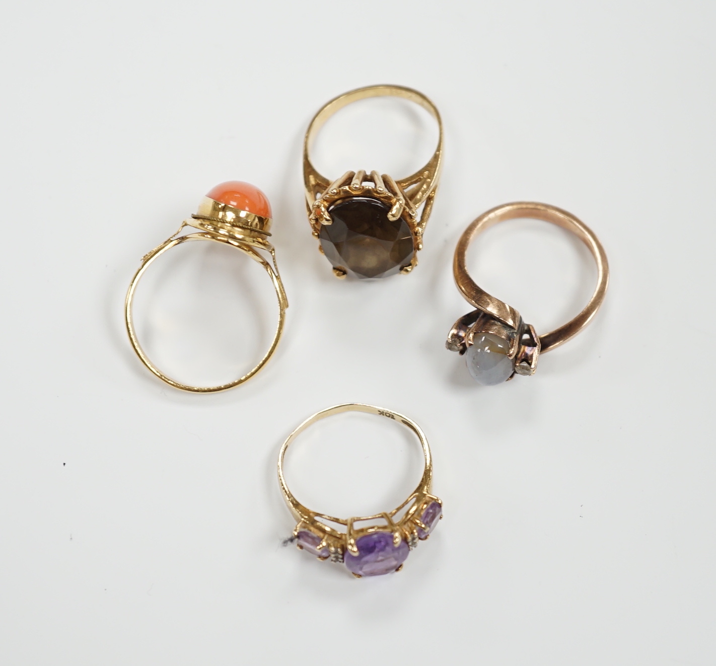 Two modern 10k and gem set rings, including amethyst and diamond chip and two yellow metal and gem set rings including coral set and star quartz? set, gross weight 15.9 grams.